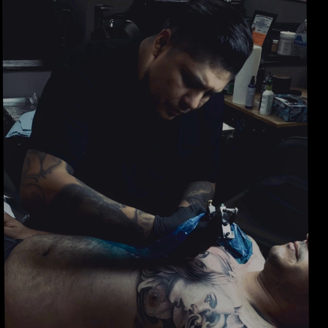 Erik Stein tattooing a black and grey realism piece in the studio.